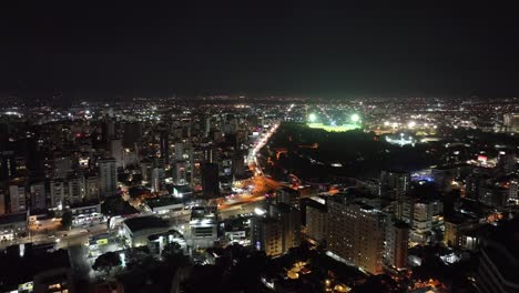 Vista-Aérea-De-Santo-Domingo,-República-Dominicana-Por-La-Noche,-Tráfico-De-Avenida-Muy-Transitada,-Edificios-Brillantes-Y-Luces