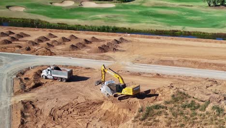 Yarrawonga,-Victoria,-Australia---8-March-2024:-Aerial-view-of-two-tip-trucks-and-an-excavator-moving-dirt-on-a-new-site-at-Silverwoods-Estate-in-Yarrawonga