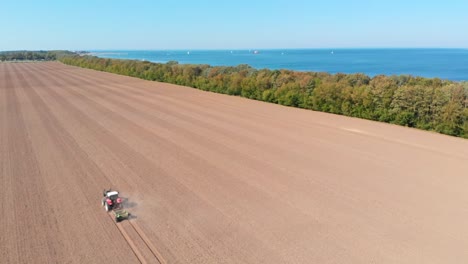 Aerial:-tractor-plowing-the-field-by-the-sea-in-Northern-Germany-in-a-sunny-day