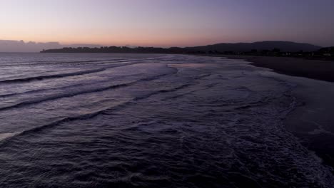 Retire-El-Disparo-De-Un-Dron-Volando-Directamente-Sobre-Una-Playa-Con-Olas-Rompiendo-Al-Atardecer