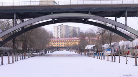 Aerial-over-white-frozen-Palsundet-reveals-Palsundsbron-with-traffic,-Stockholm