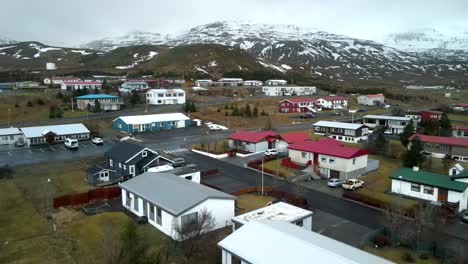 A-breathtakingly-captured,-cinematic-4K-drone-offers-an-aerial-view-of-multicolored-homes-nestled-beneath-the-Icelandic-mountains,-presenting-a-uniquely-stunning-perspective