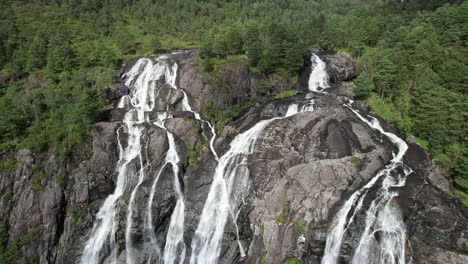 Aerial-shot,-rotating-slowly-around-the-top-of-a-large-waterfall,-Laukelandsfossen,-in-Norway