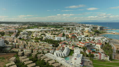 Vista-Aérea-Panorámica-De-Pernera,-Chipre,-Que-Muestra-La-Densa-Zona-Residencial,-Los-Alojamientos-Turísticos-Y-El-Vasto-Mar-Mediterráneo-Como-Telón-De-Fondo.