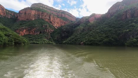 Scenic-African-boat-safari-on-Blyde-River-Canyon-below-dramatic-mountain-landscape