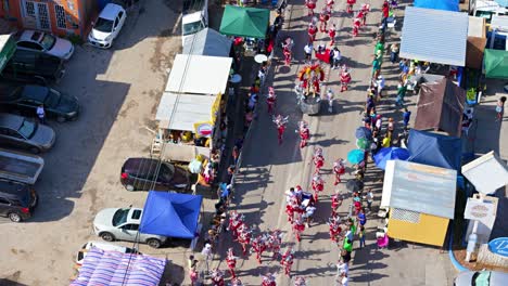 Rote-Und-Weiße-Federkostüme-Funkeln,-Während-Die-Darsteller-Beim-Großen-Karnevalsmarsch-In-Curaçao-Auf-Der-Straße-Tanzen