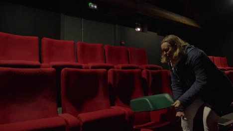Hand-held-shot-of-a-woman-putting-a-child-seat-on-a-red-cinema-chair
