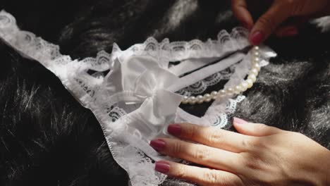 Weiße-Spitzenunterwäsche-Mit-Perlen-Von-Einer-Frauenhand-Platziert