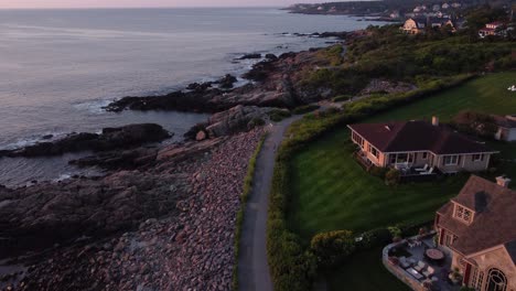 Aerial-sunset-in-Ogunquit-Maine-USA,-drone-revealing-scenic-coastline-walking-path-and-oceanfront-house-resort