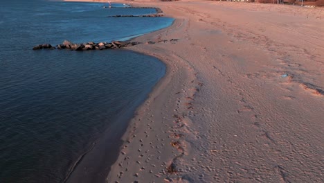 A-low-angle-view-of-the-empty-beach-on-Reynolds-Channel-in-Atlantic-Beach,-NY-during-sunrise