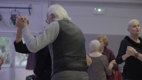 Close-up-shot-of-an-elderly-married-couple-dancing-slowly-together-in-a-hall