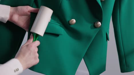 Female-Hands-Rolling-Lint-Roller-On-Surface-Of-Dry-Cleaned-Suit-At-Laundry-Shop