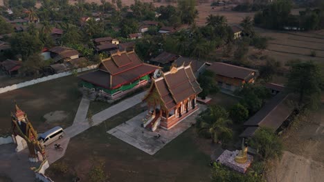 Traditionelle-Pagode-Mit-Gewölbtem-Dach-In-Der-Landschaft-Von-Lao,-Drohnenluft-Rotiert-Während-Des-Abendlichen-Sonnenlichts