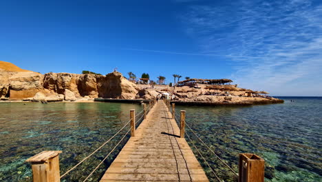 Walking-on-wooden-footbridge-to-cross-a-gulf-of-shallow-water