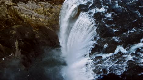 The-drone-captures-cinematic-aerial-shots-revealing-a-perilous-view-below,-where-a-rapid-waterfall-plunges-from-rugged-stone-cliffs