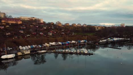 Aerial-of-boats-and-houses-on-hill-by-river-in-Stockholm-on-cloudy-day