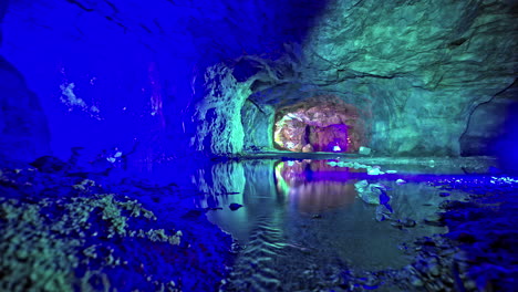 Illuminated-cave-with-reflection-in-water-in-Viking-Valley,-Norway,-serene-and-mysterious