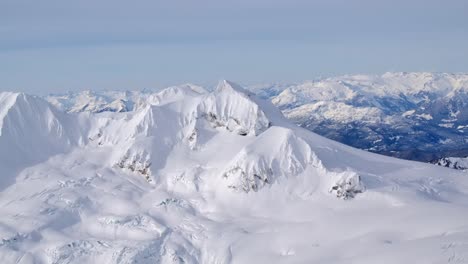 Stunning-Snowy-Winter-Mountain-Scenery,-Aerial-on-a-Sunny-Day