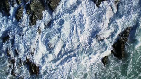 Top-Down-View-Over-Rocky-Coastline-with-Ocean-Waves-in-Slow-Motion
