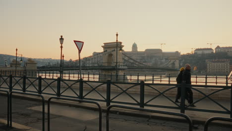 Tourists-are-walking-and-pointing-at-the-beautiful-view-by-the-Danube-river-during-sunset