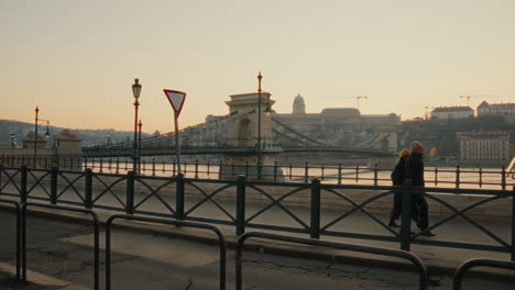 Los-Turistas-Caminan-Y-Señalan-La-Hermosa-Vista-Junto-Al-Río-Danubio-Durante-El-Atardecer.