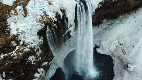 Vista-Aérea-Por-Drones-De-Una-Enorme-Cascada-En-La-Invernal-Islandia,-Tierra-De-Fuego-Y-Hielo