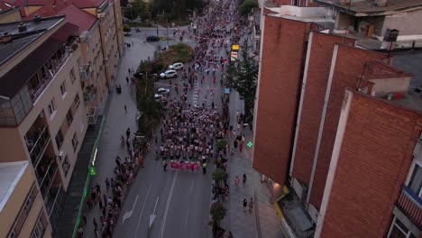 Festival-De-Folklore-Infantil-Licidersko-Srce,-Vista-Aérea-De-La-Procesión-Con-Drones,-Banderas-Y-Niños-Con-Trajes-Nacionales,-Uzice,-Serbia