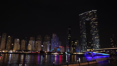 Horizonte-Del-Paisaje-Urbano-De-Dubai-Por-La-Noche,-Luces-En-Los-Rascacielos-Y-El-Paseo-Marítimo,-Vista-Desde-La-Isla-Bluewaters