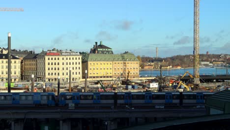 Subway-train-passes-by-Slussen-construction-site-in-Stockholm,-wide