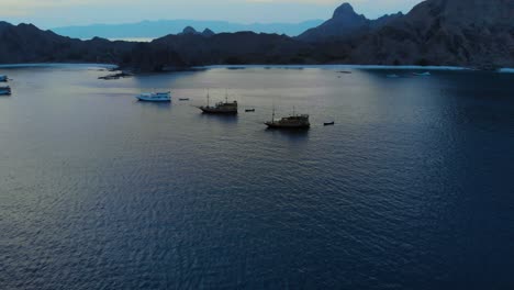 tourist-ships-at-the-coast-of-Padar-Island,-in-Komodo-National-Park-in-Indonesia,-captured-from-a-drone-during-the-evening