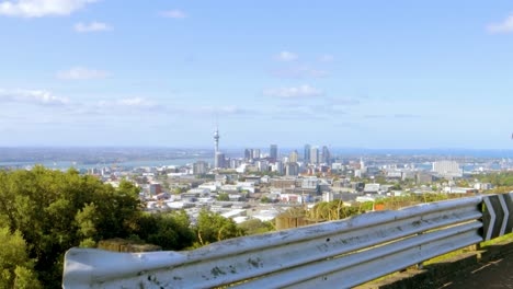 Eine-Dolly-Aufnahme-Der-Skyline-Von-Auckland-In-Neuseeland,-Gesehen-Von-Einem-Bergpfad-Aus,-Mit-Zwei-Vorbeifliegenden-Vögeln-An-Einem-Klaren-Nachmittag-Mit-Blauem-Himmel