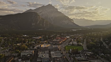 Banff-AB-Canada-Aerial-v19-flyover-the-town-capturing-forested-valley,-quaint-townscape-and-Cascade-mountain-range-during-golden-hours-of-the-morning-sunrise---Shot-with-Mavic-3-Pro-Cine---July-2023