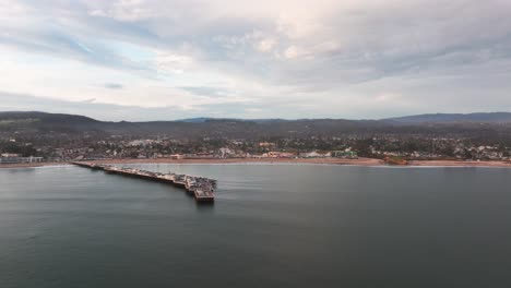 Distant-drone-shot-panning-to-the-right-of-santa-cruz-pier-and-beach-during-sunset