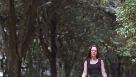 Bajo-La-Sombra-De-Los-árboles-Del-Parque-Mujer-Joven-Caminando-Hacia-Un-Lugar-Sentado