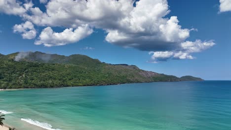 Paradise-Caribbean-beach-on-a-sunny-day,-Samaná,-Dominican-Republic,-drone-shot-revealed-looking-back