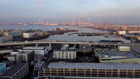 Eine-Küstenstadtlandschaft-In-Der-Abenddämmerung-Mit-Brücke-Und-Industriehafen,-Luftaufnahme