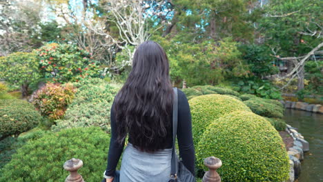 Un-Vídeo-Estabilizado-En-Cámara-Lenta-De-4k-Que-Muestra-A-Una-Hermosa-Joven-Modelo-Femenina-Del-Medio-Oriente-Explorando-Un-Exuberante-Jardín-De-Té-Japonés-Caminando-Por-Un-Sendero-De-Jardín,-Península,-California