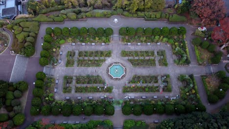 Un-Jardín-Formal-De-Diseño-Simétrico-Con-Una-Fuente-Central-Durante-El-Otoño,-Vista-Aérea