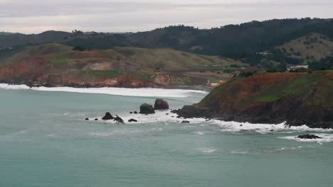 Panning-to-the-left-drone-aerial-shot-of-waves-crashing-up-on-rocky-peninsulas