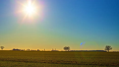 Time-lapse-of-a-glowing-sunburst-moving-over-rural-farmlands-on-a-spring-evening
