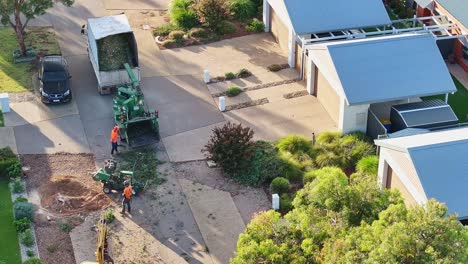 Yarrawonga,-Victoria,-Australia---6-March-2024:-Tree-worker-feeding-the-chipper-machine-while-the-stump-grinder-sets-up-in-a-suburban-street