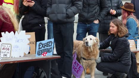 Activist-Greta-Thunberg-pets-dog-by-protest-signs-at-climate-rally