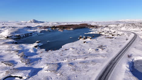 Icelandic-country-road-along-frozen-Lake-Mývatn,-aerial