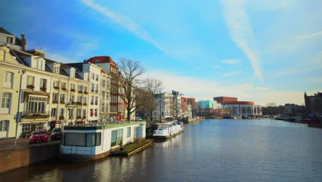 View-on-Amsterdam-Amstel-river,-canal-house-boats-and-Stopera-travel-to-right