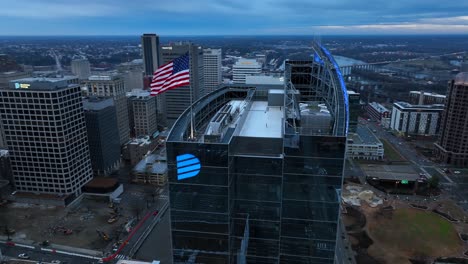 Aerial-shot-of-a-large-American-flag-on-a-skyscraper-rooftop