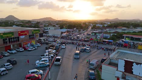 Las-Familias-Esperan-Sentadas-En-El-Borde-De-Una-Carretera-Con-Barricadas-Para-La-Gran-Marcha-Del-Carnaval-Al-Atardecer-En-Curazao.