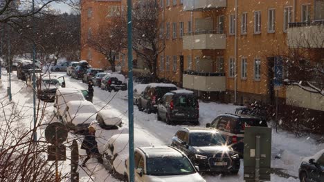 Car-traffic-on-snowy-city-street-in-sunny-winter-Stockholm,-Sweden