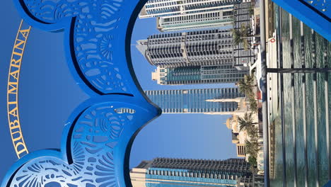 Vertikales-Video,-Dubai-Marina-Schild-Und-Luxuriöse-Wohnwolkenkratzer-Und-Türme-An-Einem-Sonnigen-Tag