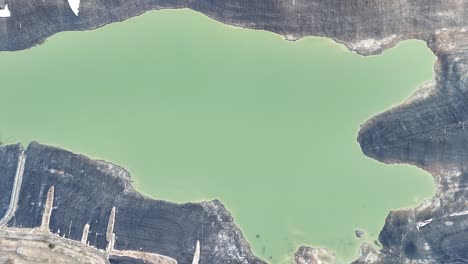 Aerial-forest-by-the-lake,-green-forest-image-with-a-shore-to-turquoise-lake-water