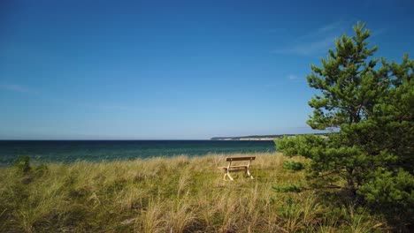 Bench-overlooking-the-Baltic-Sea-on-Gotland,-sunny-day,-calm-and-serene-scene,-wide-shot